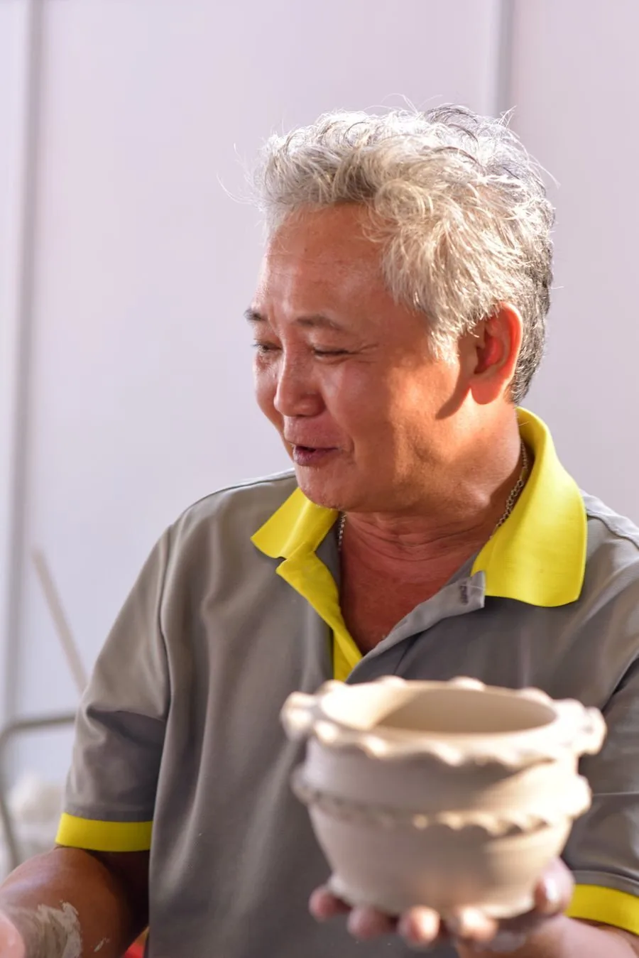 A potter smiling, holding the bowl he just made.