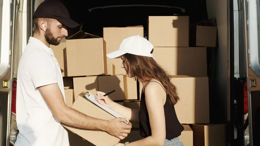 A driver getting a delivery signed for at the back of the van.