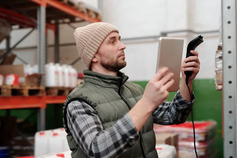 A warehouse worker scanning a barcode among the shelves.